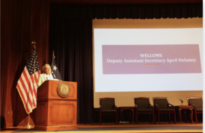This is a photograph of April McClain Delaney, a former U.S. Commerce Department undersecretary, giving a speech. 